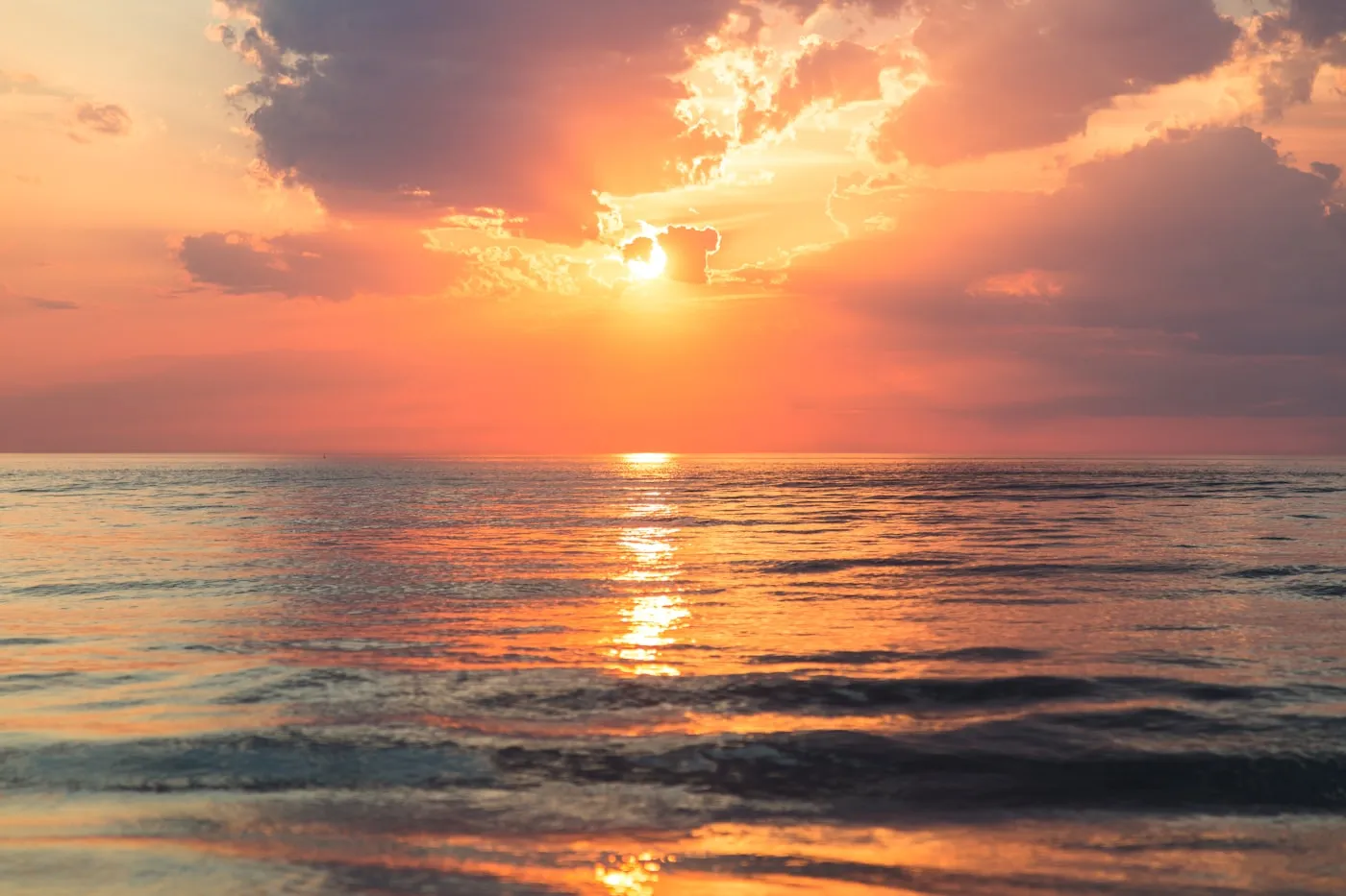 First light of sunrise over calm open water.